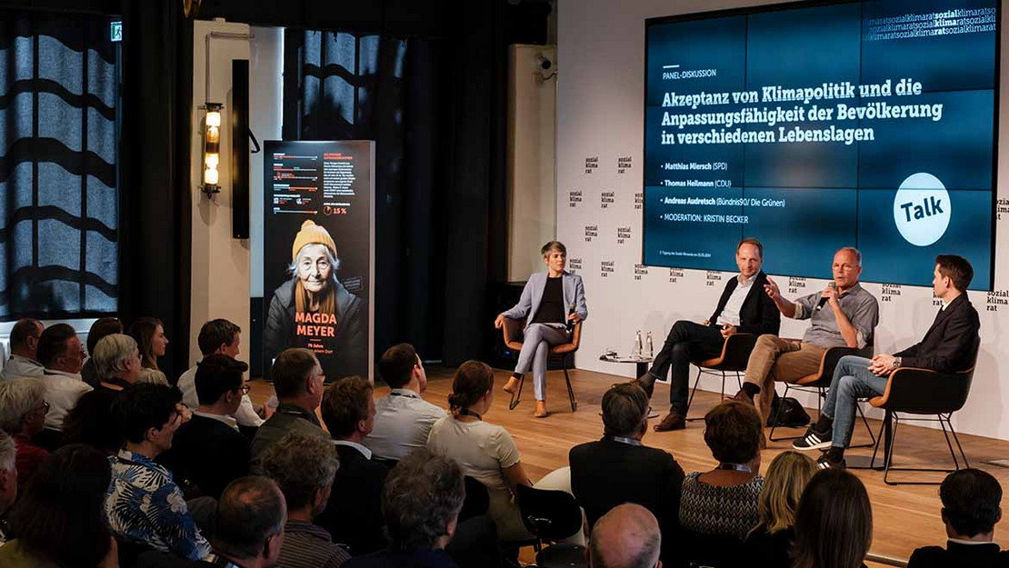 Mehrere Personen diskutieren auf einer Bühne.