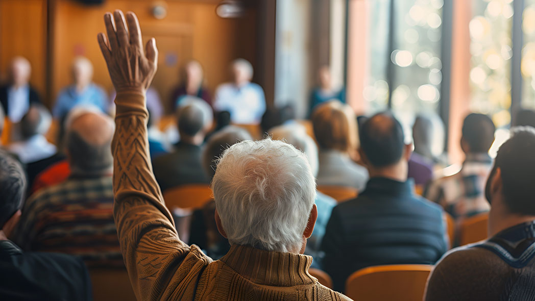 Menschen im Saal, Mann hält Hand hoch